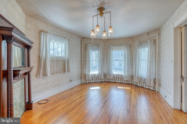 unfurnished dining area with a chandelier and light wood-type flooring