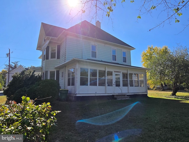 back of property featuring a lawn and a sunroom