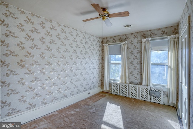 spare room featuring carpet, a wealth of natural light, and ceiling fan