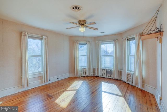 empty room with ceiling fan, a healthy amount of sunlight, and light hardwood / wood-style floors