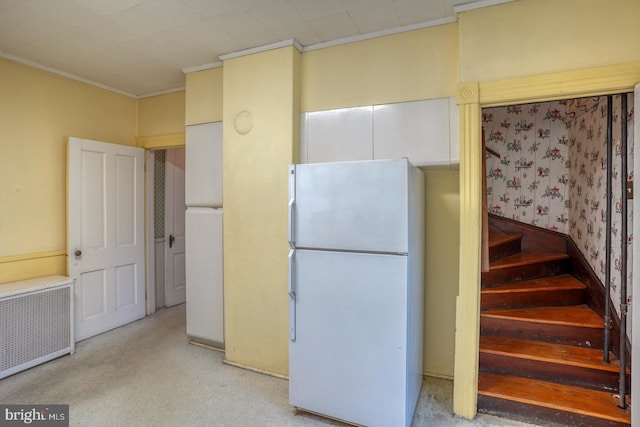 kitchen with carpet, crown molding, radiator heating unit, and white fridge