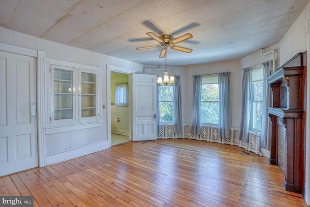 unfurnished dining area featuring light hardwood / wood-style floors and ceiling fan with notable chandelier