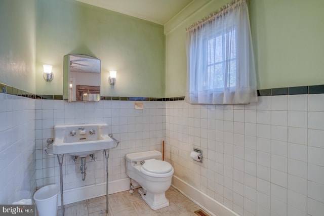 bathroom with tile patterned floors, toilet, sink, and tile walls