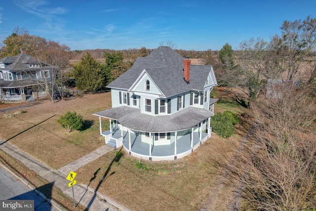 back of property with a lawn and a porch