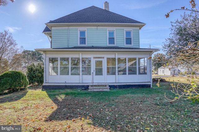 rear view of house featuring a lawn and a sunroom