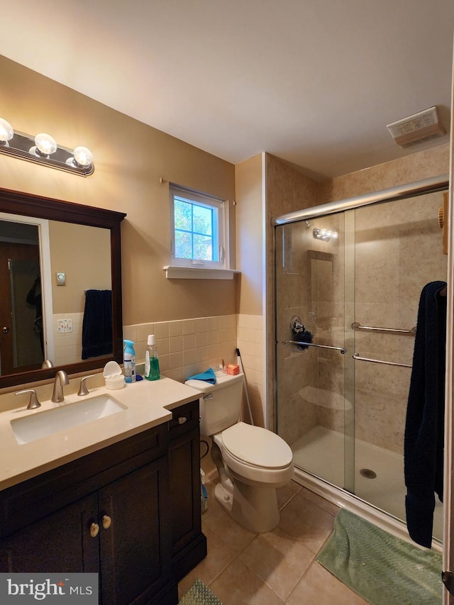 bathroom with tile patterned floors, toilet, vanity, tile walls, and walk in shower