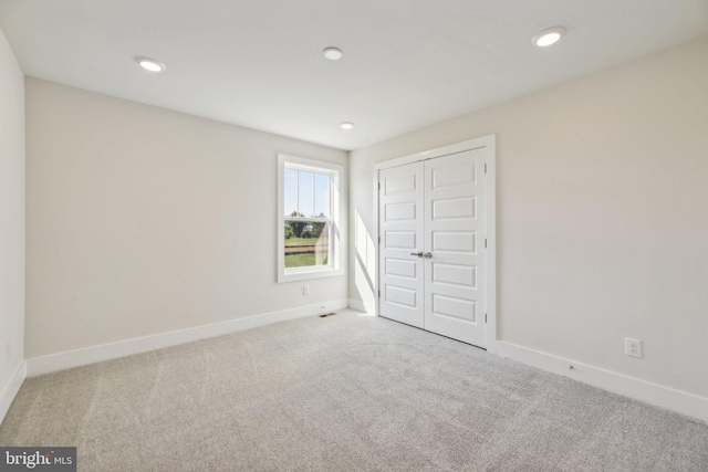 unfurnished bedroom with light carpet and a closet