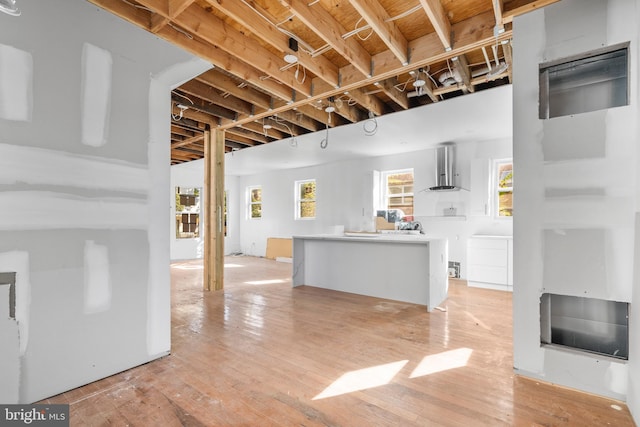 kitchen featuring wall chimney range hood and light hardwood / wood-style flooring