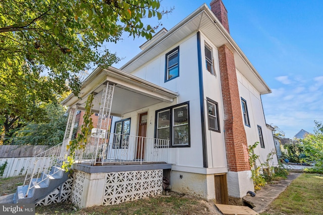 view of front facade featuring a chimney and a porch