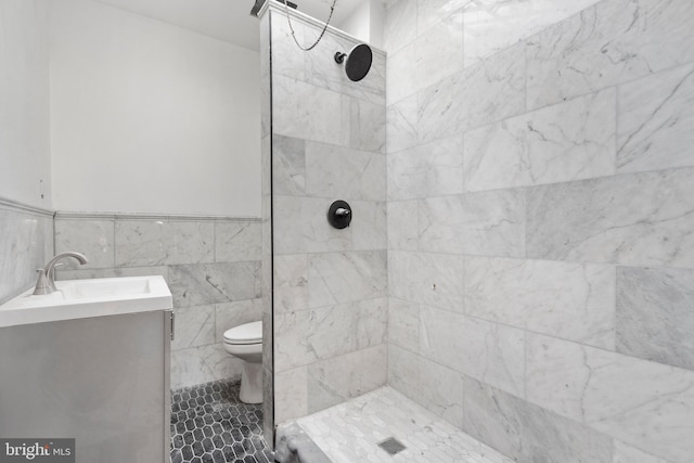 bathroom with vanity, tile walls, tiled shower, and toilet