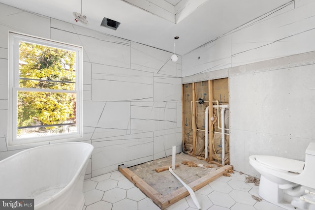 bathroom with toilet, a bath, tile walls, and a wealth of natural light