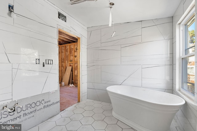 bathroom featuring a bathtub, tile patterned floors, and tile walls