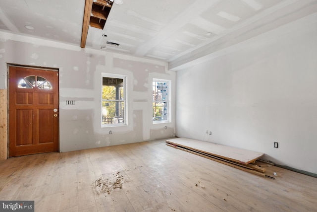 entryway with beamed ceiling and light wood-type flooring