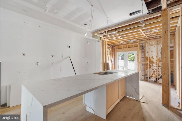 kitchen featuring a kitchen island, light stone counters, and french doors