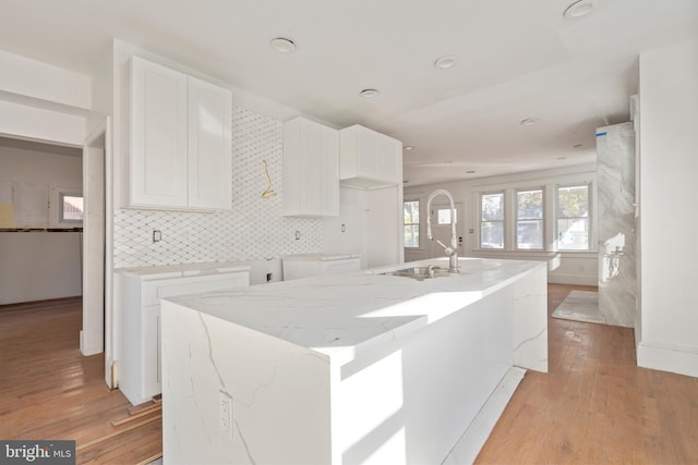 kitchen featuring light hardwood / wood-style floors, white cabinetry, sink, and a center island with sink