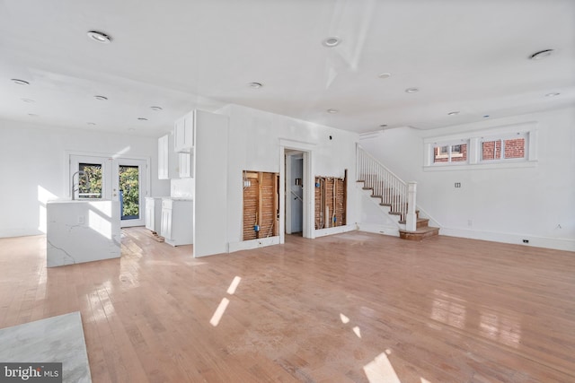 unfurnished living room with light wood-style floors, baseboards, stairs, and recessed lighting