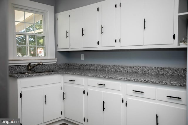 kitchen featuring sink, white cabinetry, and dark stone countertops