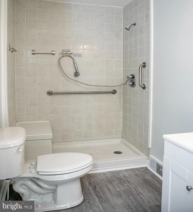 bathroom featuring vanity, toilet, hardwood / wood-style flooring, and a tile shower