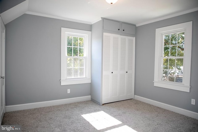 unfurnished bedroom with a closet, crown molding, multiple windows, and light colored carpet