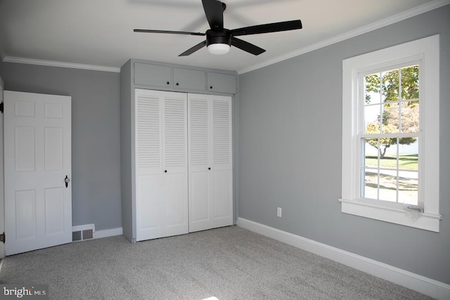 unfurnished bedroom with crown molding, light colored carpet, a closet, and ceiling fan