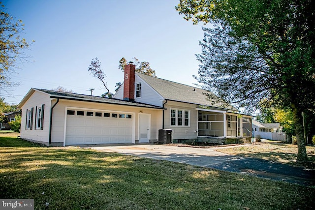 view of front of property featuring a sunroom, a front lawn, central AC unit, and a garage