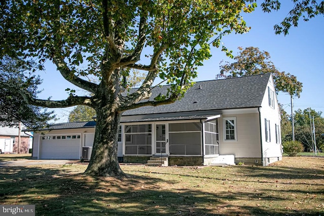 view of front of property featuring a sunroom, a front yard, and a garage