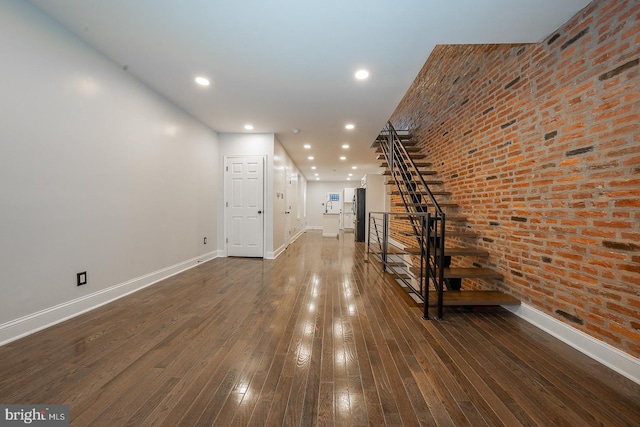 interior space with dark hardwood / wood-style floors and brick wall