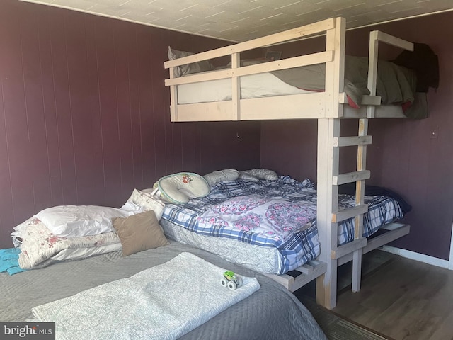 bedroom with hardwood / wood-style floors and wood walls