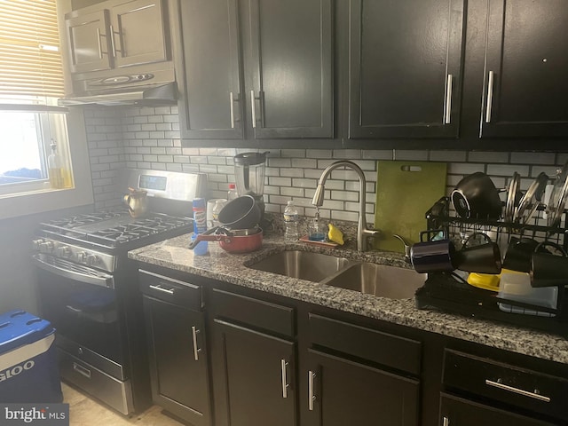 kitchen featuring sink, stainless steel gas stove, light stone counters, and tasteful backsplash