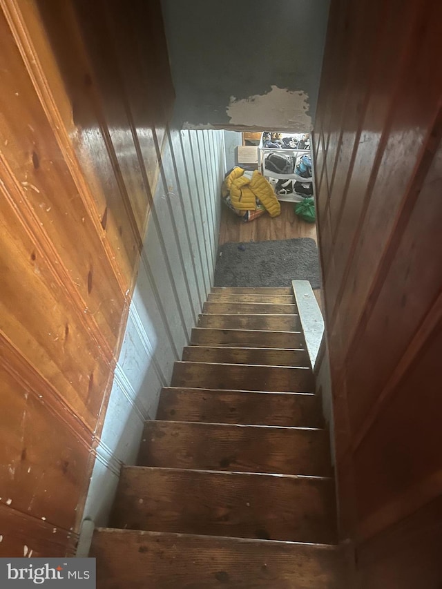 stairway featuring wood walls