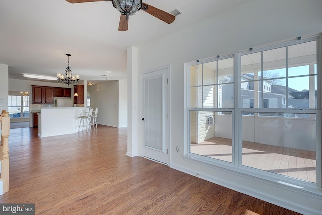 interior space featuring ceiling fan with notable chandelier and light hardwood / wood-style flooring