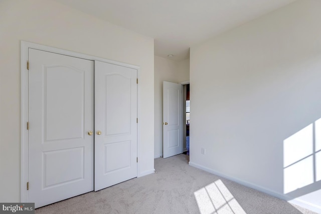 unfurnished bedroom with light carpet and a closet