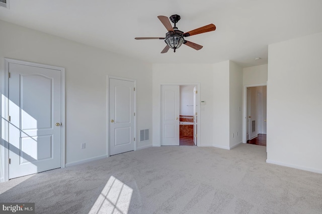 unfurnished bedroom featuring ensuite bathroom, light colored carpet, and ceiling fan