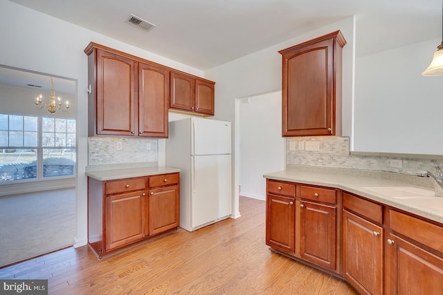 kitchen featuring tasteful backsplash, decorative light fixtures, light hardwood / wood-style floors, and white fridge