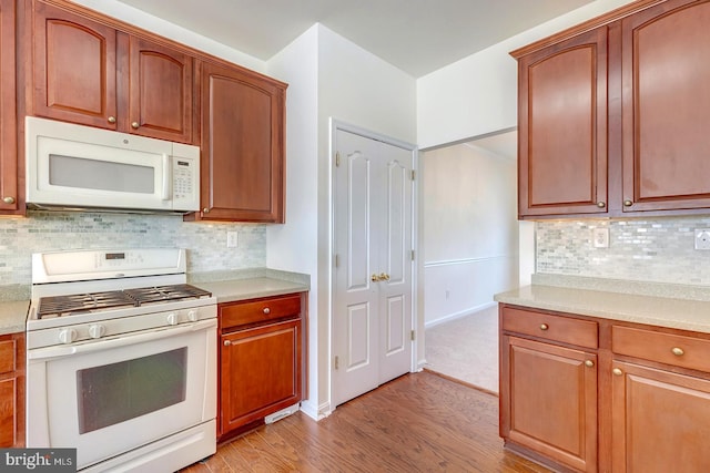 kitchen with decorative backsplash, white appliances, and light hardwood / wood-style flooring