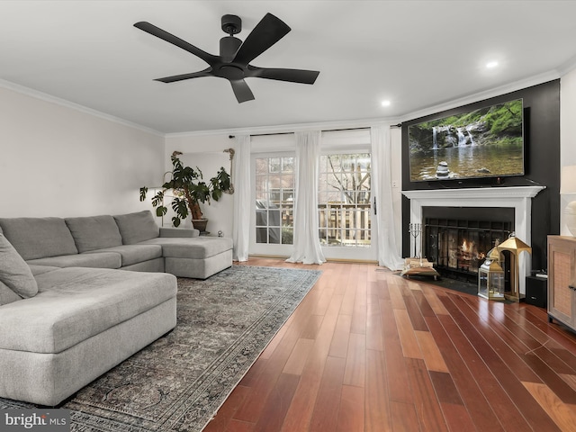 living room with hardwood / wood-style flooring, ceiling fan, and ornamental molding