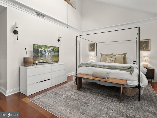 bedroom with dark wood-type flooring, ceiling fan, and a high ceiling