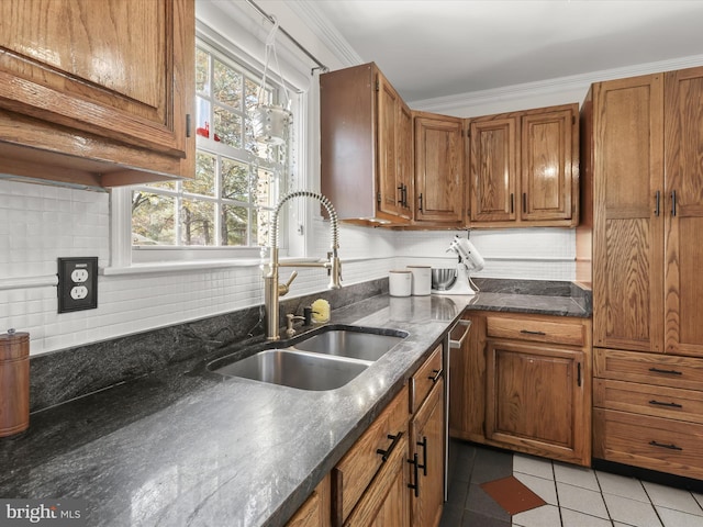 kitchen featuring sink, crown molding, light tile patterned floors, dark stone counters, and backsplash