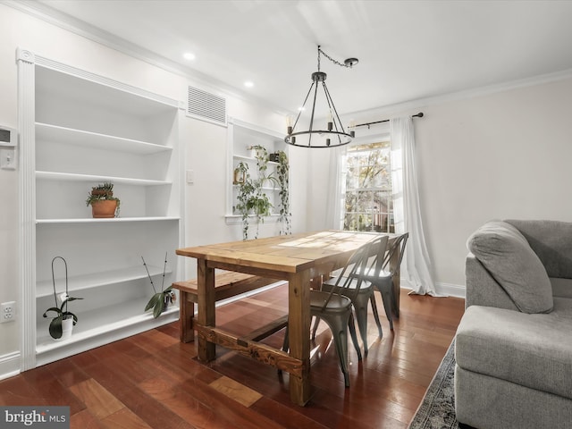 dining room featuring dark hardwood / wood-style flooring, a notable chandelier, built in features, and ornamental molding