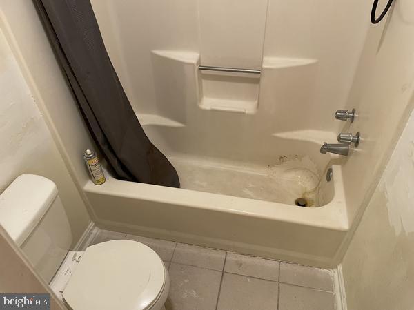 bathroom with tile patterned flooring, toilet, and shower / bath combo with shower curtain