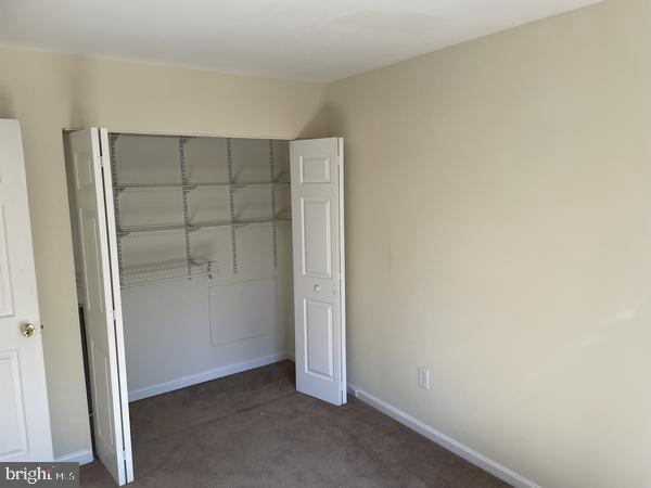 unfurnished bedroom featuring a closet and dark colored carpet