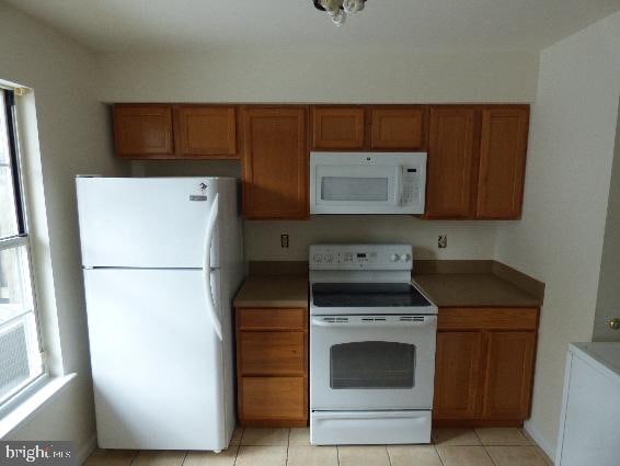 kitchen with light tile patterned flooring, a healthy amount of sunlight, and white appliances