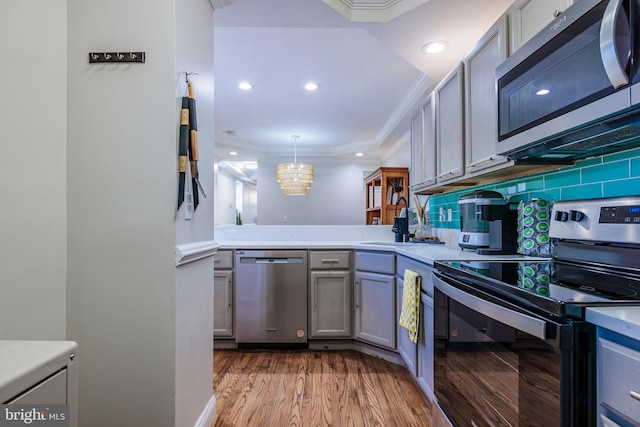 kitchen with dark hardwood / wood-style flooring, gray cabinetry, ornamental molding, pendant lighting, and appliances with stainless steel finishes