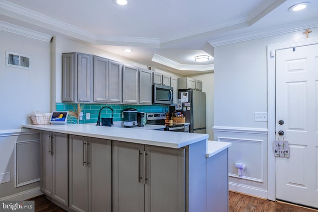 kitchen featuring stainless steel appliances, kitchen peninsula, crown molding, gray cabinets, and dark hardwood / wood-style flooring