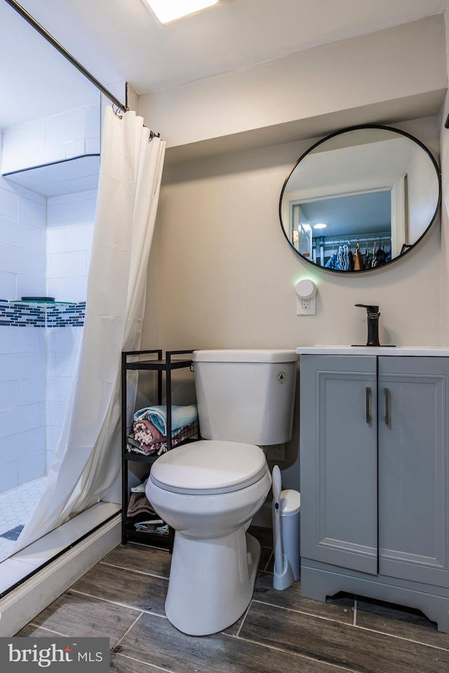 bathroom with hardwood / wood-style flooring, vanity, curtained shower, and toilet