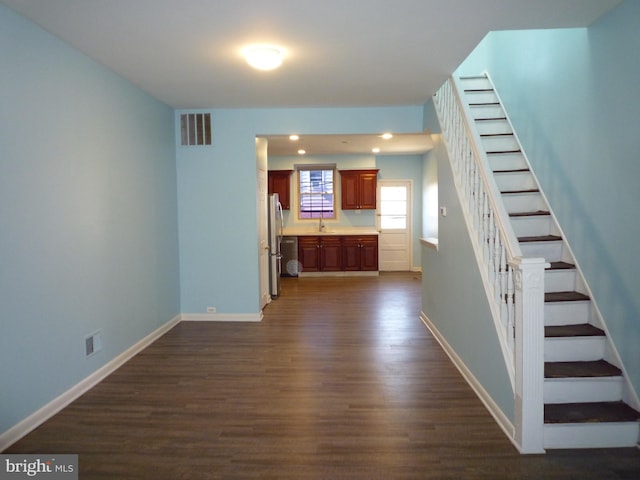 unfurnished living room featuring sink and dark hardwood / wood-style floors