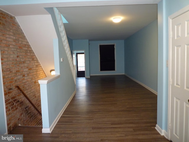 corridor featuring brick wall and dark hardwood / wood-style flooring