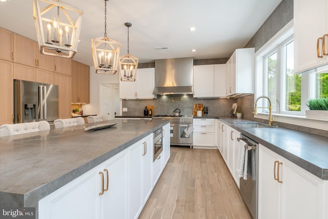 kitchen featuring a spacious island, high quality appliances, white cabinets, and wall chimney range hood