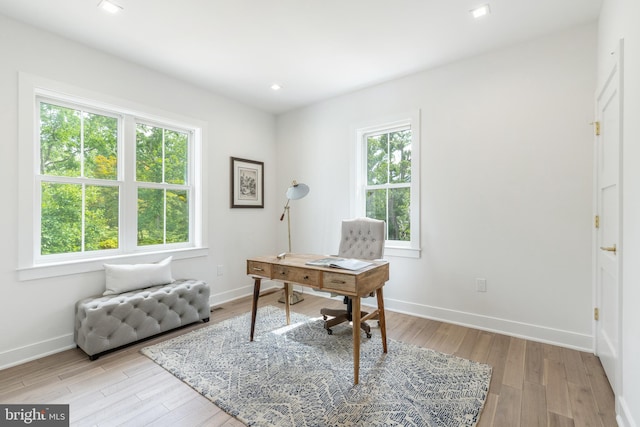 home office with light hardwood / wood-style flooring and a healthy amount of sunlight