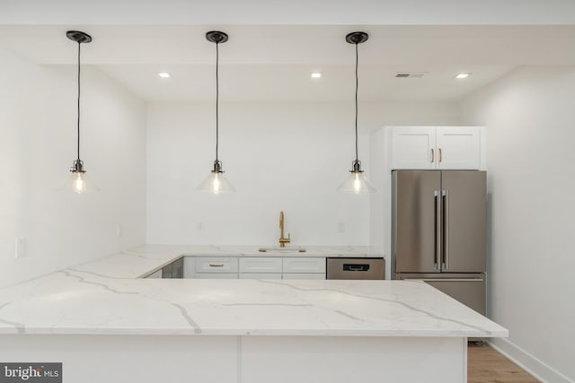 kitchen with kitchen peninsula, white cabinets, light stone counters, sink, and stainless steel appliances